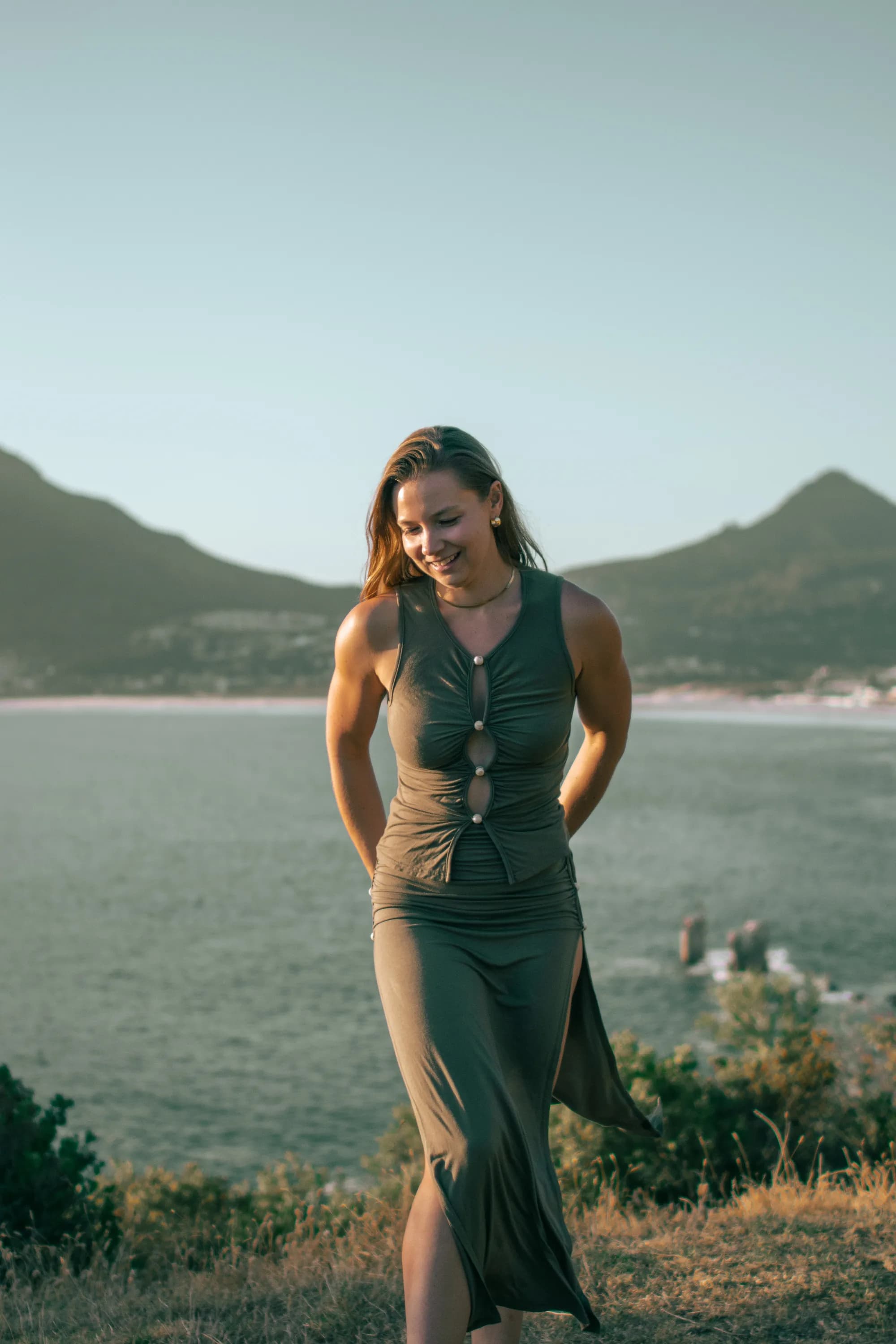 Madison looking down in a dress with the ocean behind her